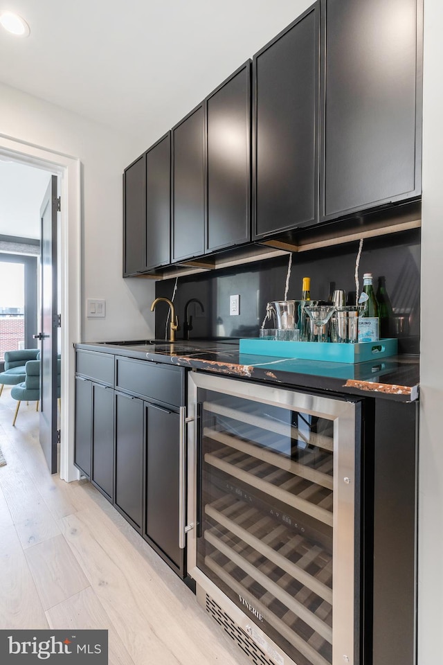 bar with wine cooler and light wood-type flooring