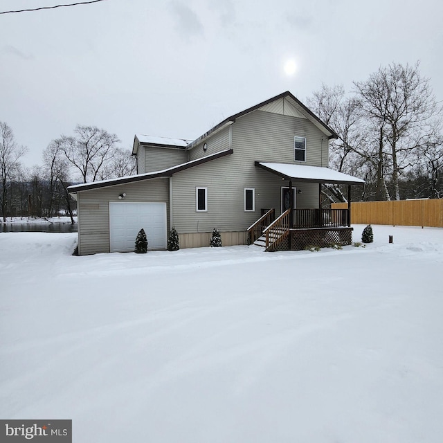 snow covered back of property featuring a garage