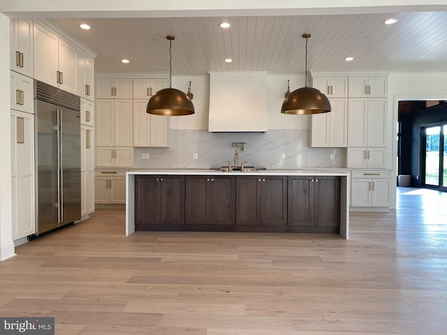 kitchen with backsplash, light hardwood / wood-style floors, decorative light fixtures, built in fridge, and white cabinetry