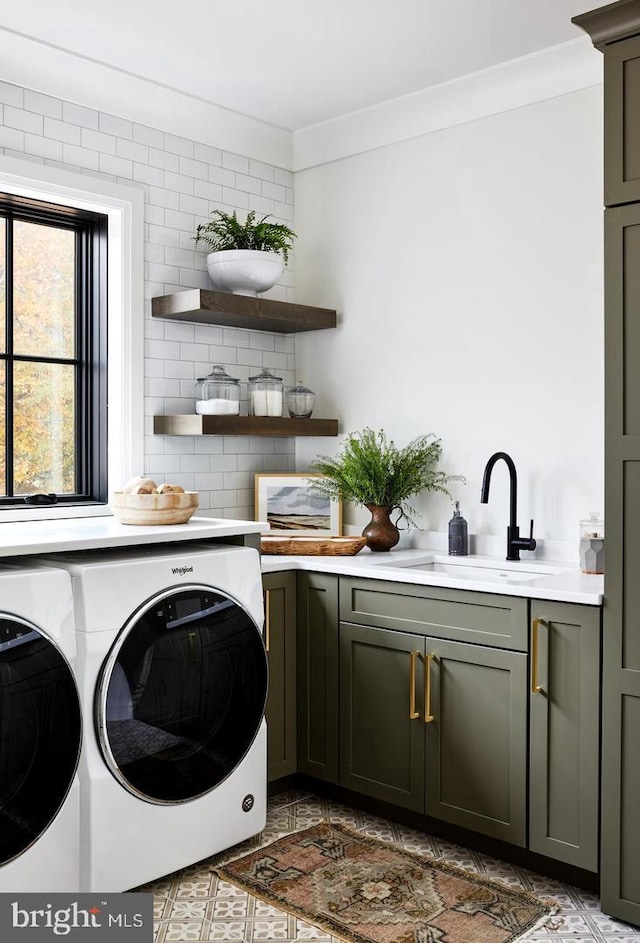 washroom featuring washer and dryer, sink, dark tile flooring, ornamental molding, and cabinets