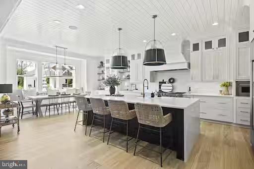 kitchen featuring white cabinetry, light hardwood / wood-style flooring, a breakfast bar area, and a kitchen island with sink