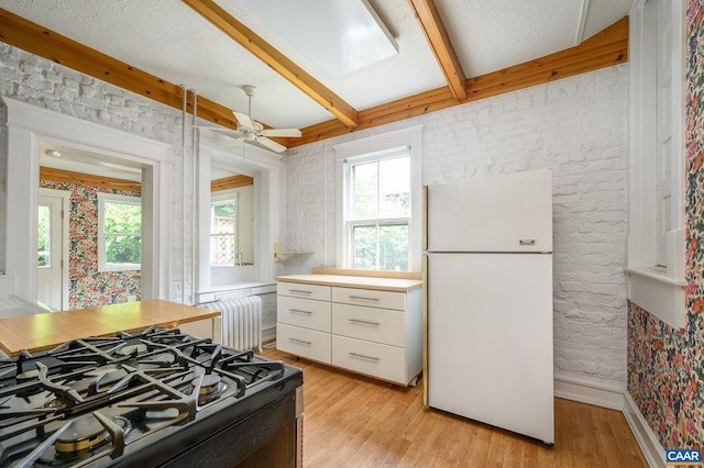 kitchen with white fridge, light wood-type flooring, radiator, stove, and ceiling fan