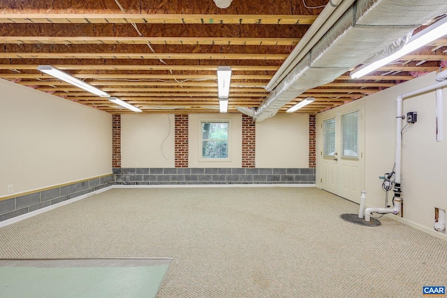 basement featuring brick wall and carpet floors