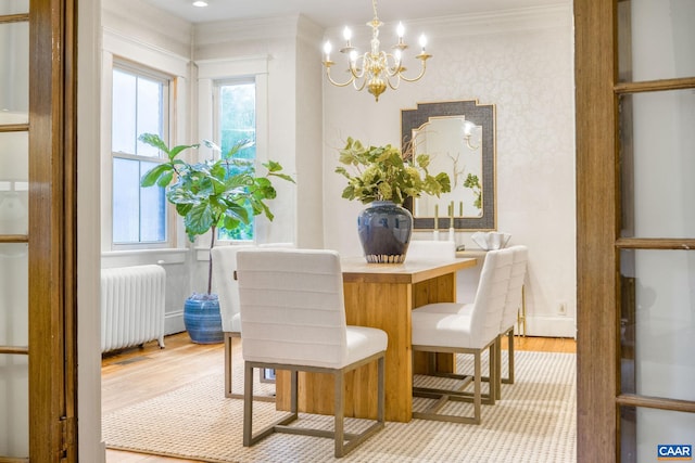 dining area featuring crown molding, light hardwood / wood-style floors, an inviting chandelier, and radiator heating unit