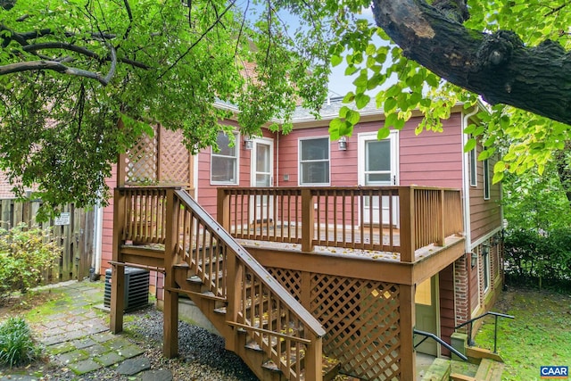 back of property featuring fence, a deck, central air condition unit, and stairs