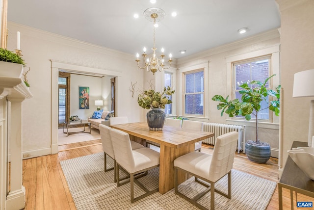 dining room with an inviting chandelier, light hardwood / wood-style flooring, crown molding, and radiator heating unit