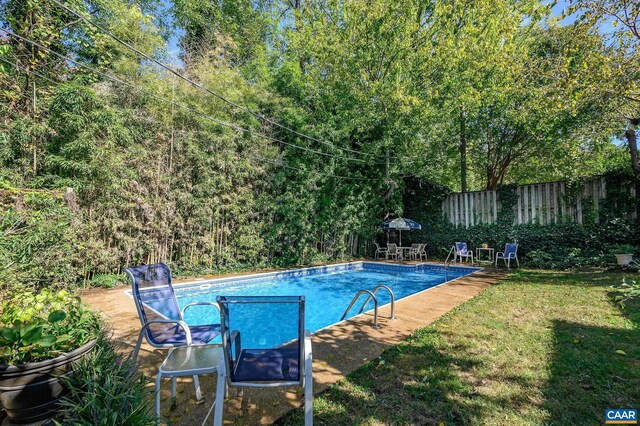 pool featuring a patio area, fence, and a lawn
