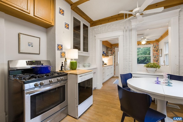 kitchen with gas stove, light hardwood / wood-style floors, ornamental molding, white dishwasher, and ceiling fan