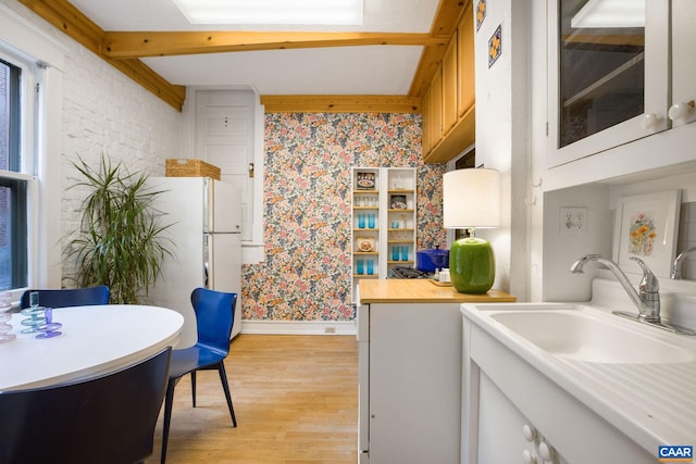 kitchen featuring brick wall, sink, and light hardwood / wood-style floors