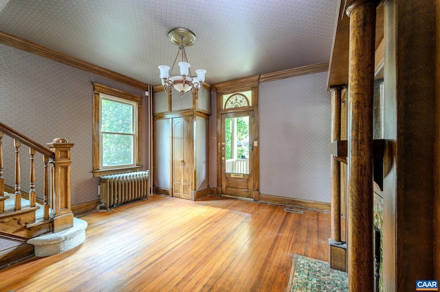 entrance foyer featuring light hardwood / wood-style floors, an inviting chandelier, radiator heating unit, and a wealth of natural light