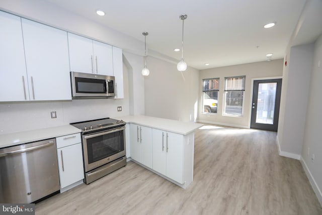 kitchen featuring decorative light fixtures, white cabinetry, appliances with stainless steel finishes, and light wood-type flooring