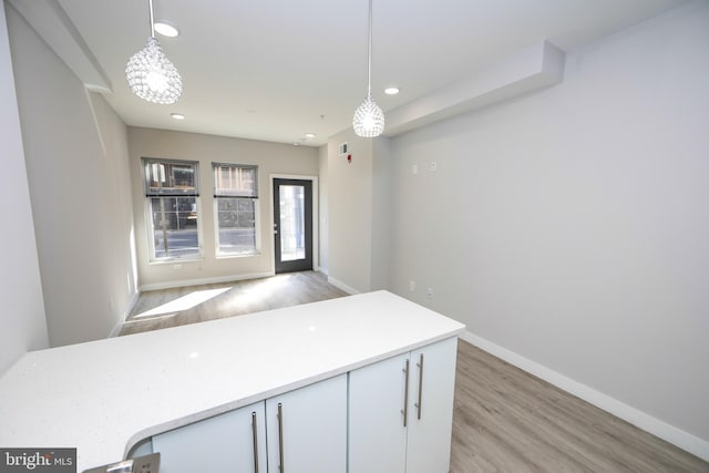 unfurnished room featuring a chandelier and light hardwood / wood-style flooring