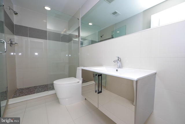 bathroom with toilet, a shower with door, tile walls, sink, and tile floors