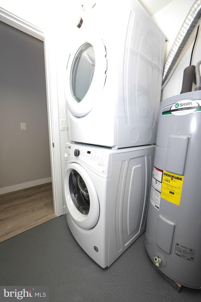 laundry area featuring dark hardwood / wood-style flooring, stacked washer / drying machine, and electric water heater