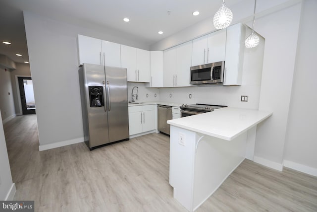 kitchen featuring appliances with stainless steel finishes, decorative light fixtures, light hardwood / wood-style floors, and tasteful backsplash