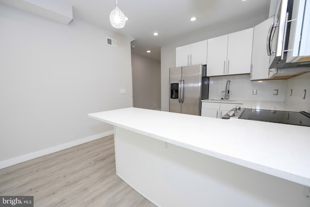 kitchen featuring decorative light fixtures, appliances with stainless steel finishes, light wood-type flooring, white cabinets, and tasteful backsplash