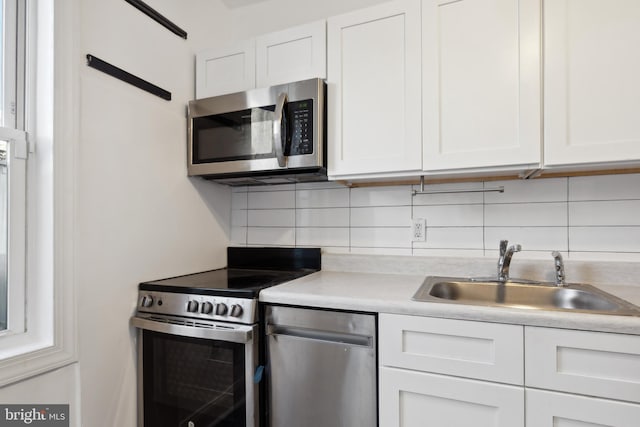 kitchen featuring backsplash, white cabinetry, appliances with stainless steel finishes, and sink