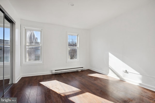 spare room featuring dark wood-type flooring and baseboard heating