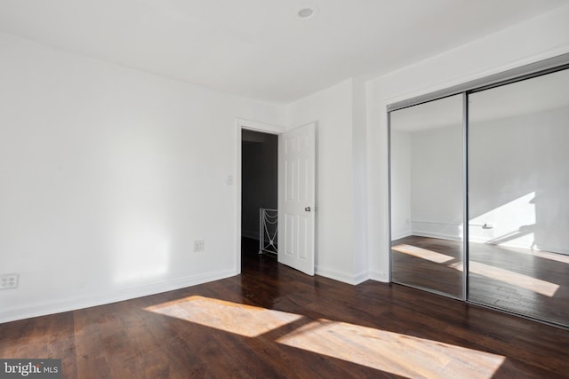 unfurnished bedroom with a closet and dark wood-type flooring