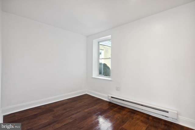 empty room featuring dark hardwood / wood-style floors and a baseboard heating unit