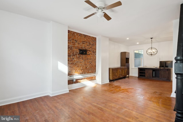 unfurnished living room with brick wall, hardwood / wood-style flooring, and ceiling fan with notable chandelier