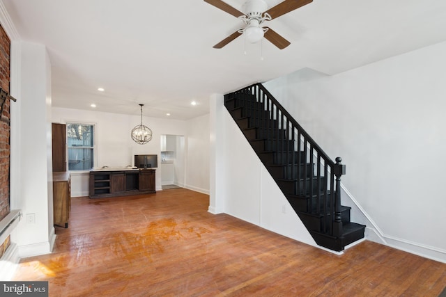 stairway featuring ceiling fan with notable chandelier and light hardwood / wood-style floors