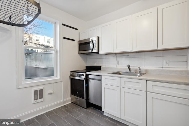 kitchen featuring appliances with stainless steel finishes, sink, backsplash, and white cabinetry