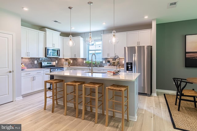 kitchen featuring hanging light fixtures, a center island with sink, and appliances with stainless steel finishes