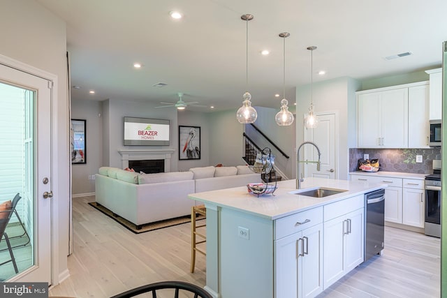 kitchen featuring white cabinetry, backsplash, appliances with stainless steel finishes, sink, and pendant lighting