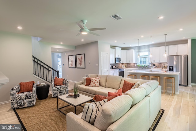 living room with ceiling fan, sink, and light hardwood / wood-style floors