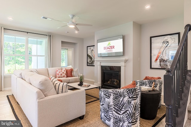 living room featuring ceiling fan, light wood-type flooring, and a fireplace