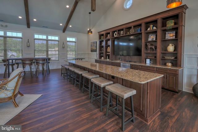 bar with dark hardwood / wood-style floors, beam ceiling, light stone counters, dishwasher, and pendant lighting