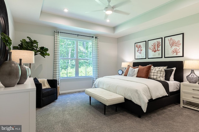 carpeted bedroom featuring ceiling fan and a tray ceiling