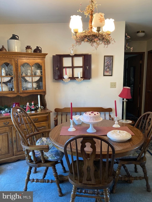 dining space with an inviting chandelier and dark carpet