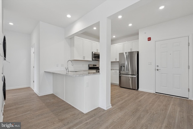 16423 River View Dr, Bristol, PA 19007 - kitchen with stainless steel appliances, light wood-style floors, a peninsula, white cabinets, and a sink