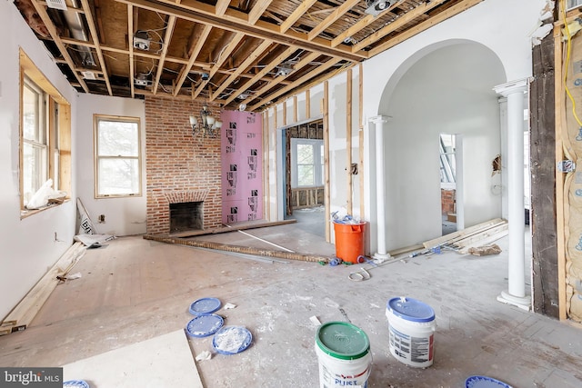 miscellaneous room with brick wall, decorative columns, and a fireplace