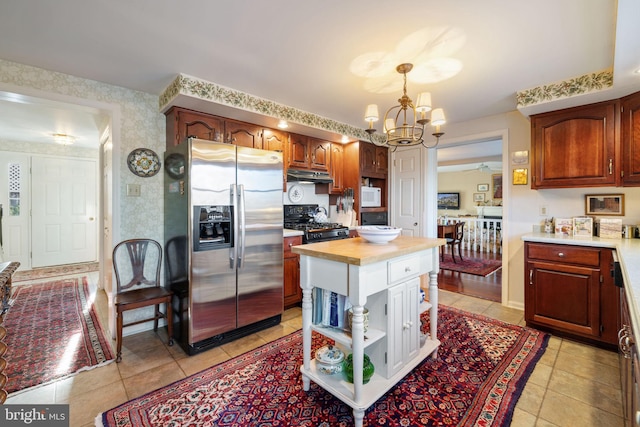 kitchen featuring pendant lighting, black gas stove, light tile floors, and stainless steel fridge with ice dispenser