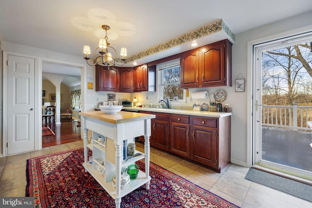 kitchen featuring light tile floors, hanging light fixtures, sink, and a chandelier