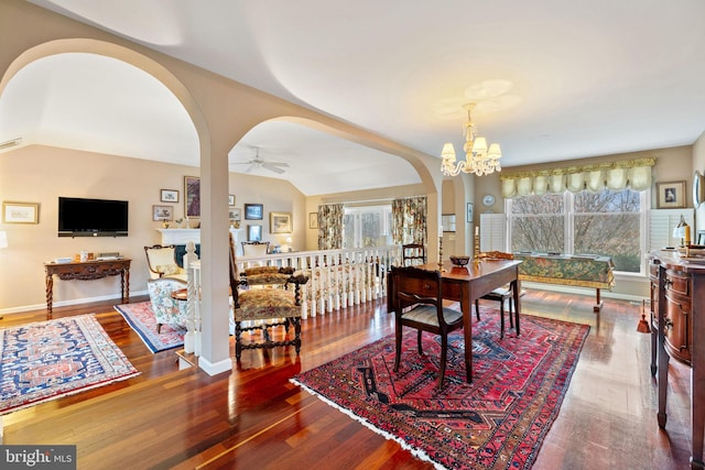 dining area featuring lofted ceiling, ceiling fan with notable chandelier, and dark hardwood / wood-style floors