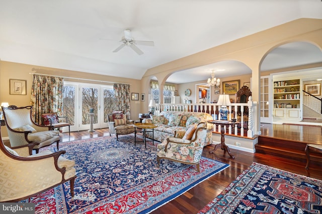 living room featuring lofted ceiling, built in features, dark hardwood / wood-style floors, and ceiling fan with notable chandelier