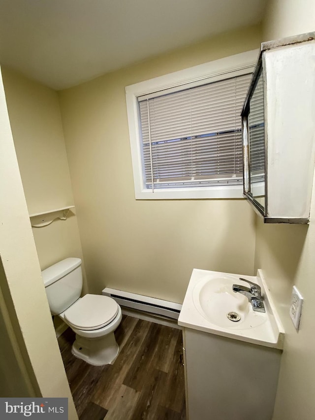 bathroom featuring toilet, oversized vanity, a baseboard heating unit, and wood-type flooring