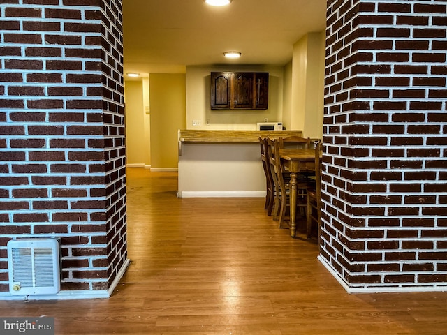 interior space featuring brick wall, dark hardwood / wood-style flooring, and dark brown cabinetry