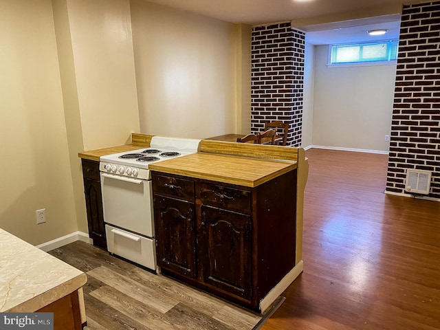 kitchen with brick wall, white range oven, dark brown cabinets, and dark hardwood / wood-style flooring