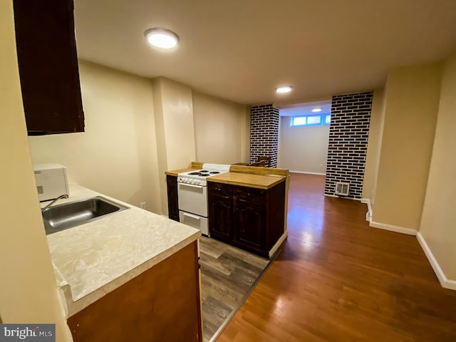 kitchen with dark wood-type flooring, white appliances, brick wall, sink, and dark brown cabinets