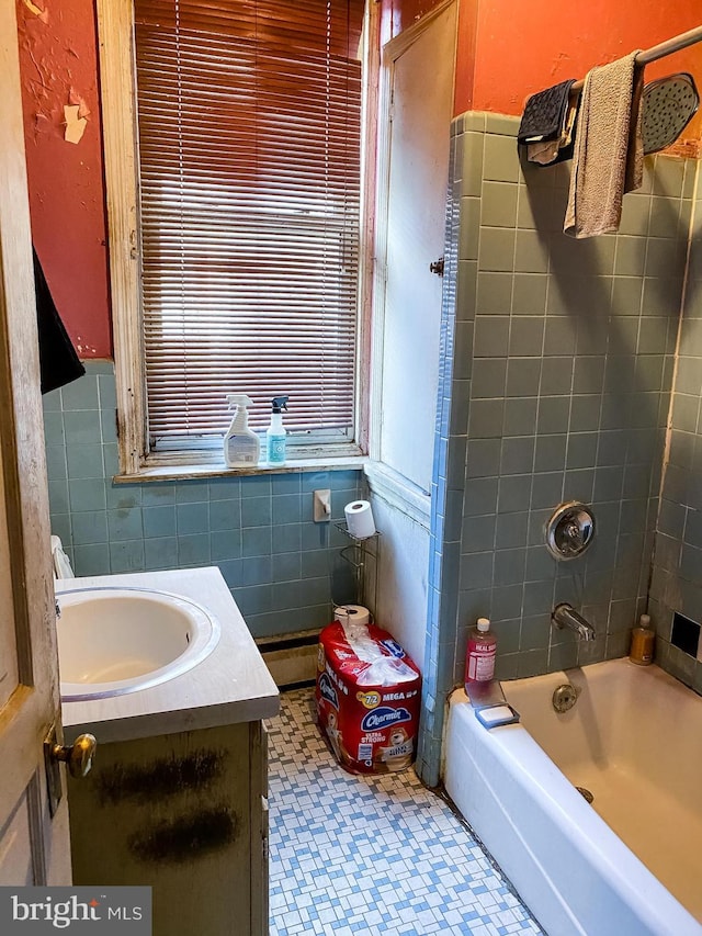 bathroom with tile walls, tile flooring, tiled shower / bath combo, and vanity