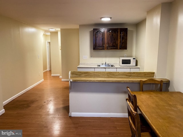 kitchen with sink, dark brown cabinets, and dark wood-type flooring