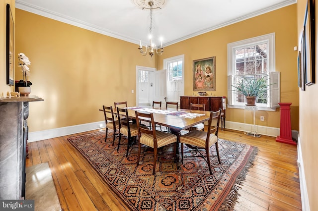 dining room with ornamental molding, a notable chandelier, and light hardwood / wood-style flooring