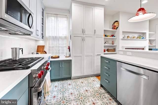 kitchen with hanging light fixtures, white cabinetry, appliances with stainless steel finishes, and decorative backsplash