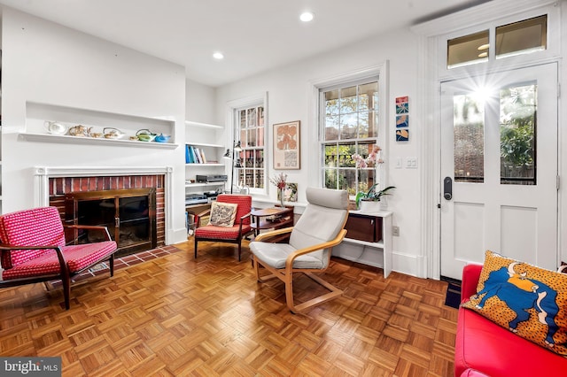 sitting room featuring parquet flooring and a brick fireplace