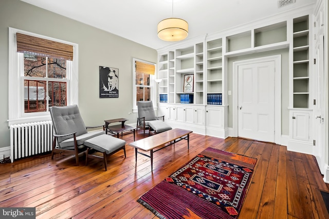 living room with hardwood / wood-style flooring, radiator heating unit, and built in shelves